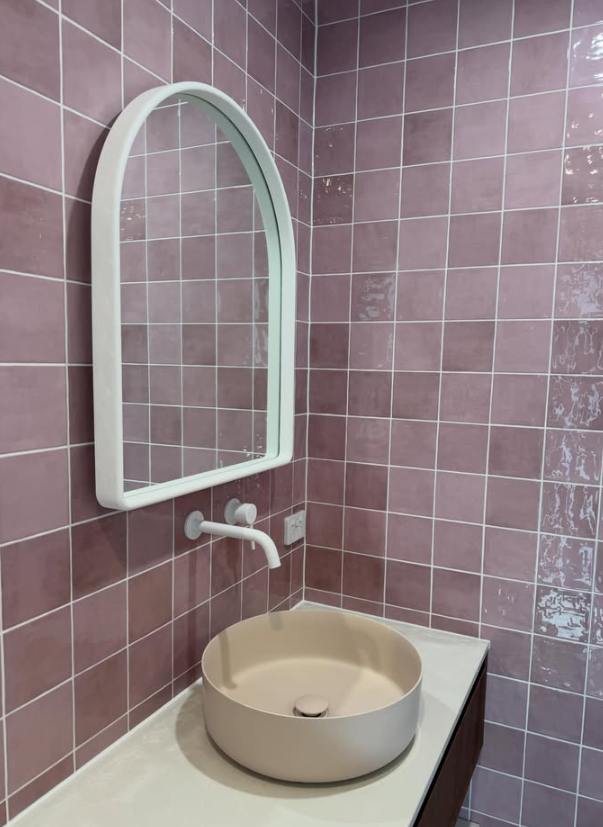 Bathroom with rose tiles and arched mirror