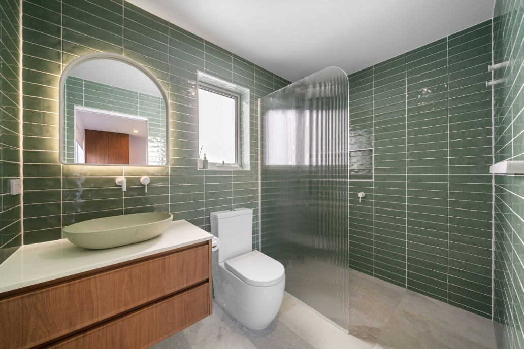 Green tiled bathroom with arched mirror